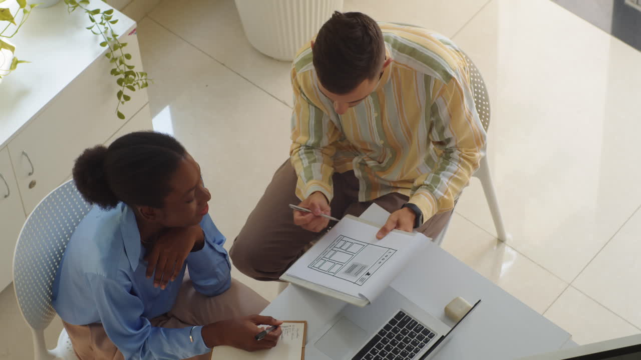 Biracial Developers Discussing App Mockup Screen Top View