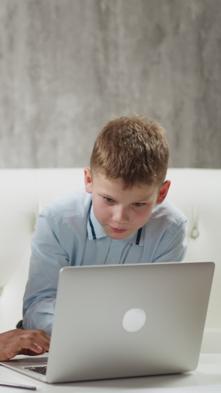 African-American English teacher shows educative materials on laptop computer to attentive little boy student during private lesson at home slow motion