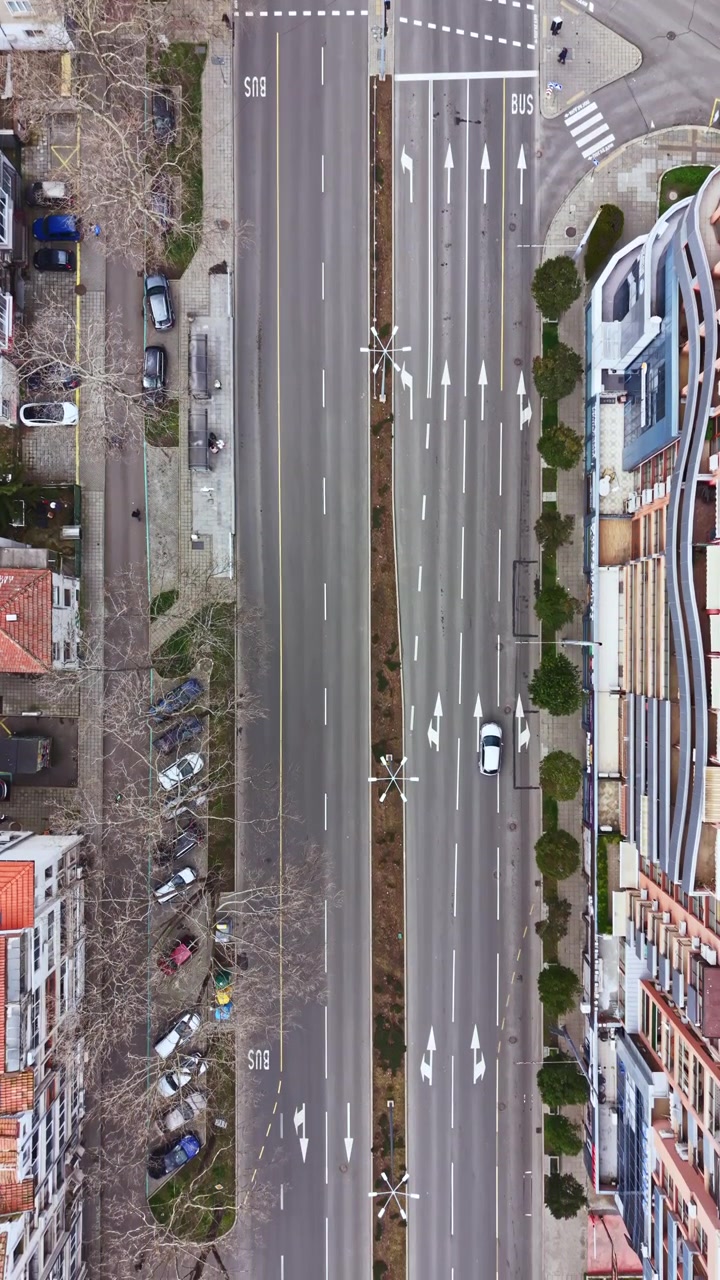Verkeer stroomt op een brede stadsstraat met meerdere rijstroken en duidelijke busroutes in een moderne stedelijke omgeving overdag.