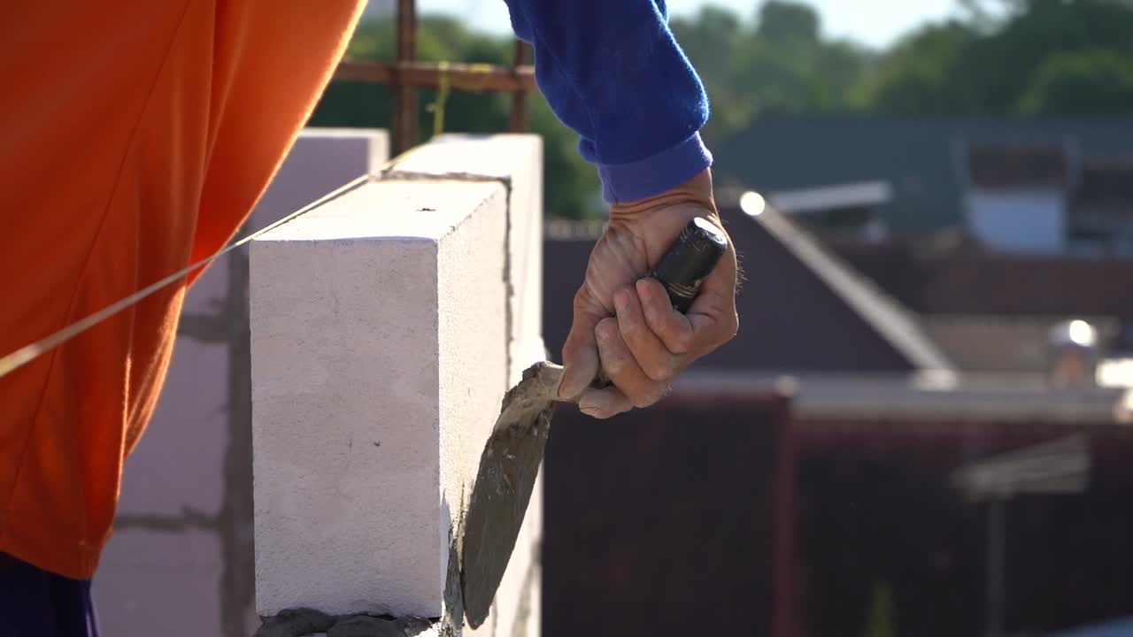 A worker applying cement to a pile of bricks