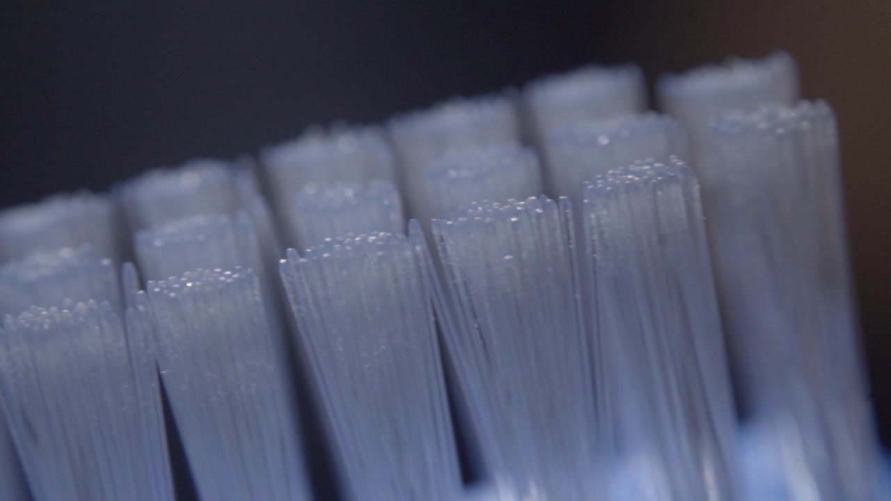 Primo piano con panoramica di fitte setole bianche disposte in file. Fibre sottili e traslucide e punte texturizzate creano un motivo ripetitivo sul materiale compatto.