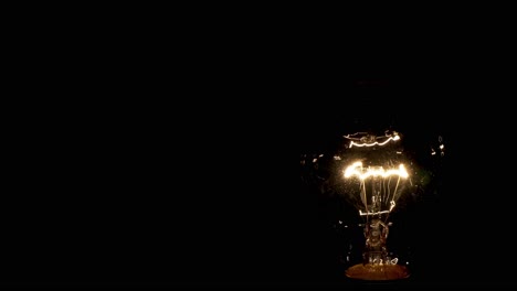 Concept-design-of-electricity-on-incandescent-lamps-with-orange-tungsten-filament-moving-slowly-on-black-background