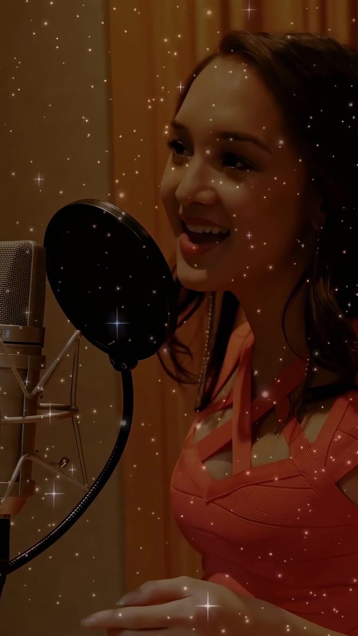 Woman vocalist entering and leaning to pop filter, singing into mic, recording with starry overlay
