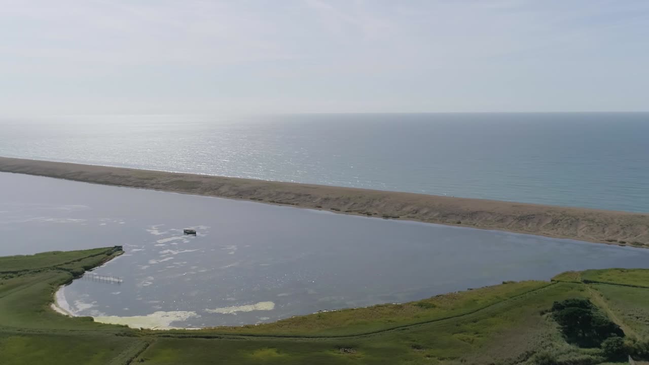 Ripresa aerea rotante e in tracciamento da destra a sinistra sopra la laguna di Fleet, vicino alla Abbotsbury Swannery, accanto a Chesil Beach, Dorset.