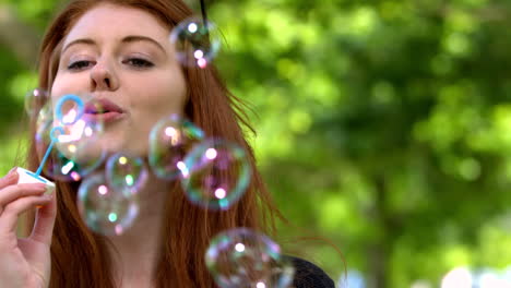 pretty redhead blowing bubbles in the park