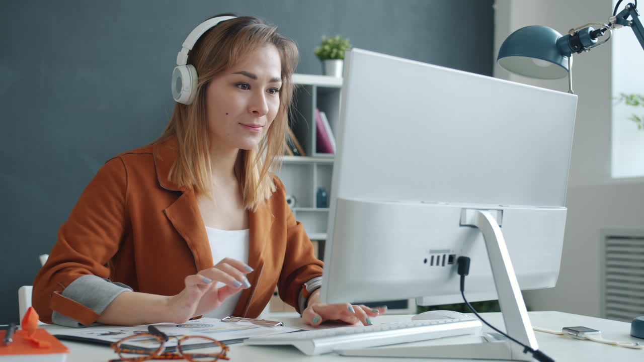 Woman working on computer wearing headphones