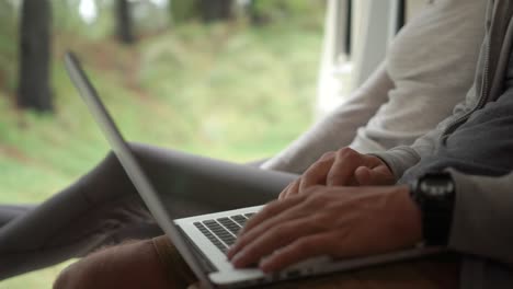 primer plano en cámara lenta: una pareja sentada en la parte trasera de su autocaravana hablando y mirando una computadora
