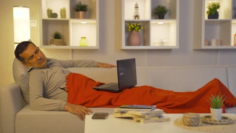man using laptop lying down falls asleep.