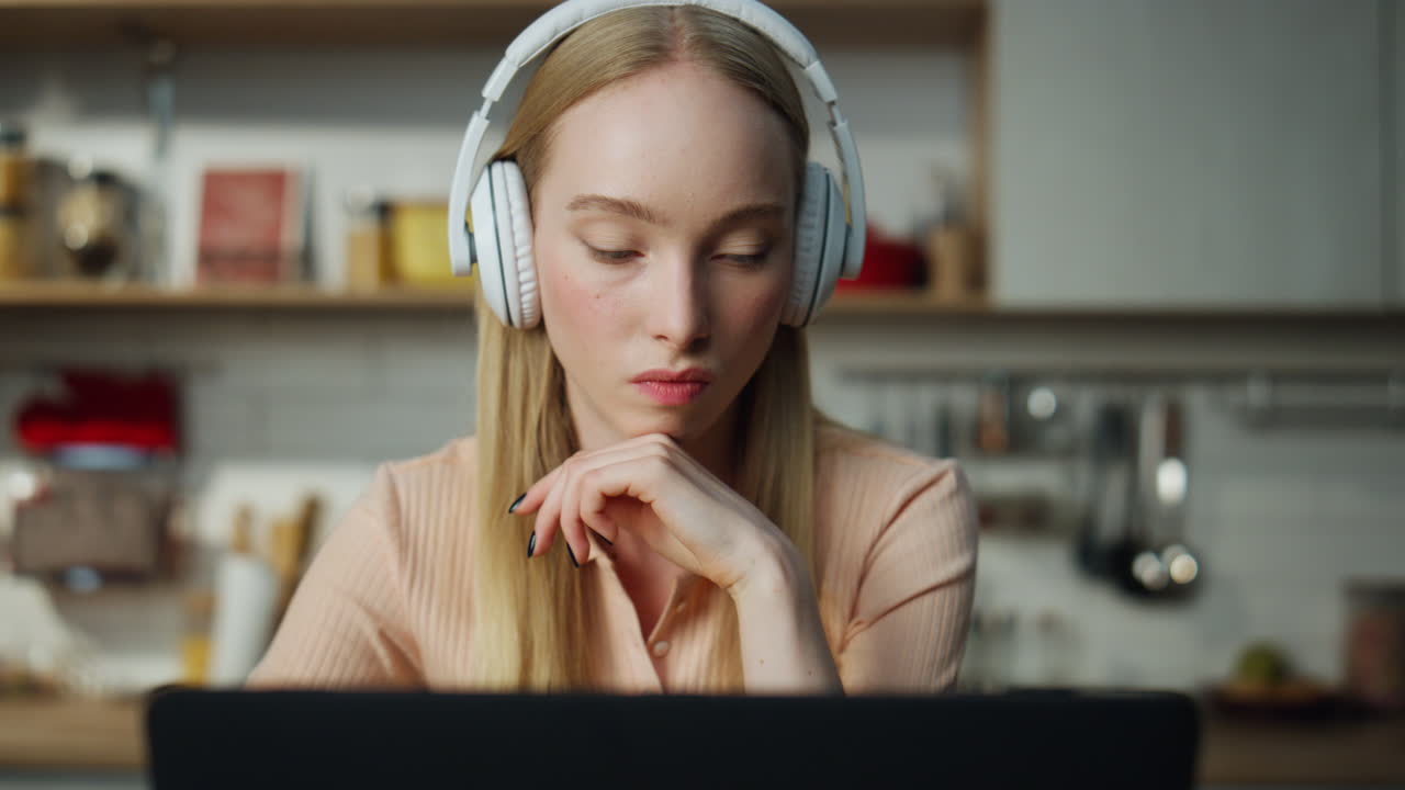 Girl looking laptop screen searching in internet listening music by headphones