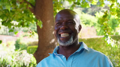 portrait of smiling senior man standing outdoors in garden park or countryside