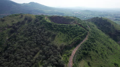 mountain-with-a-hole-at-the-peak-and-a-water-filled-crater,-captured-with-a-forward-camera-movement-revealing-the-crater's-opening