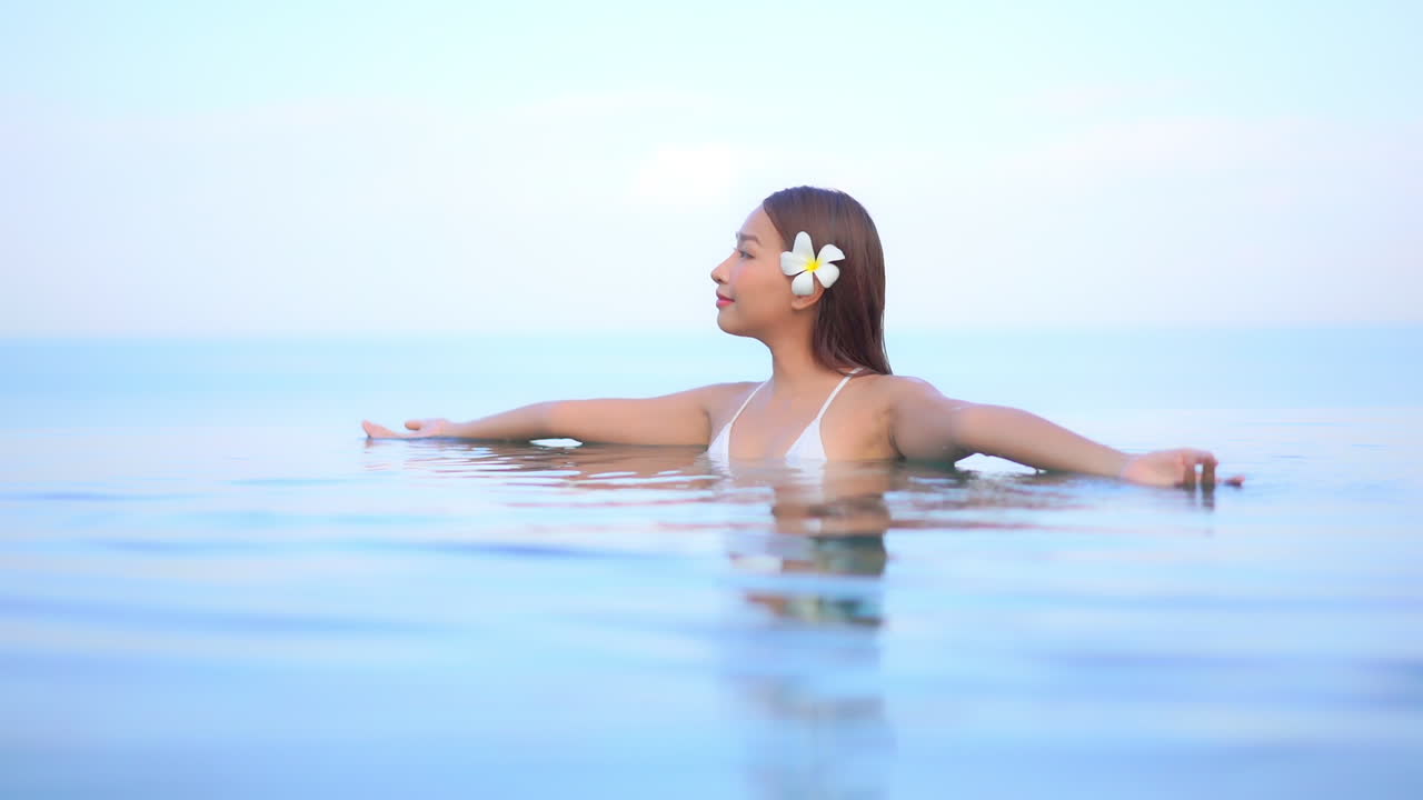 수영장에서 가슴 높이의 아름다운 여성이 팔을 들어 하루를 맞이합니다.