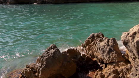 Waves-Gently-Crashing-Into-Rocks-In-Bay-of-Ieranto,-Italy