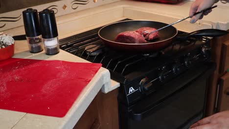 feminine hands moving seasoned steaks from cutting board to hot skillet