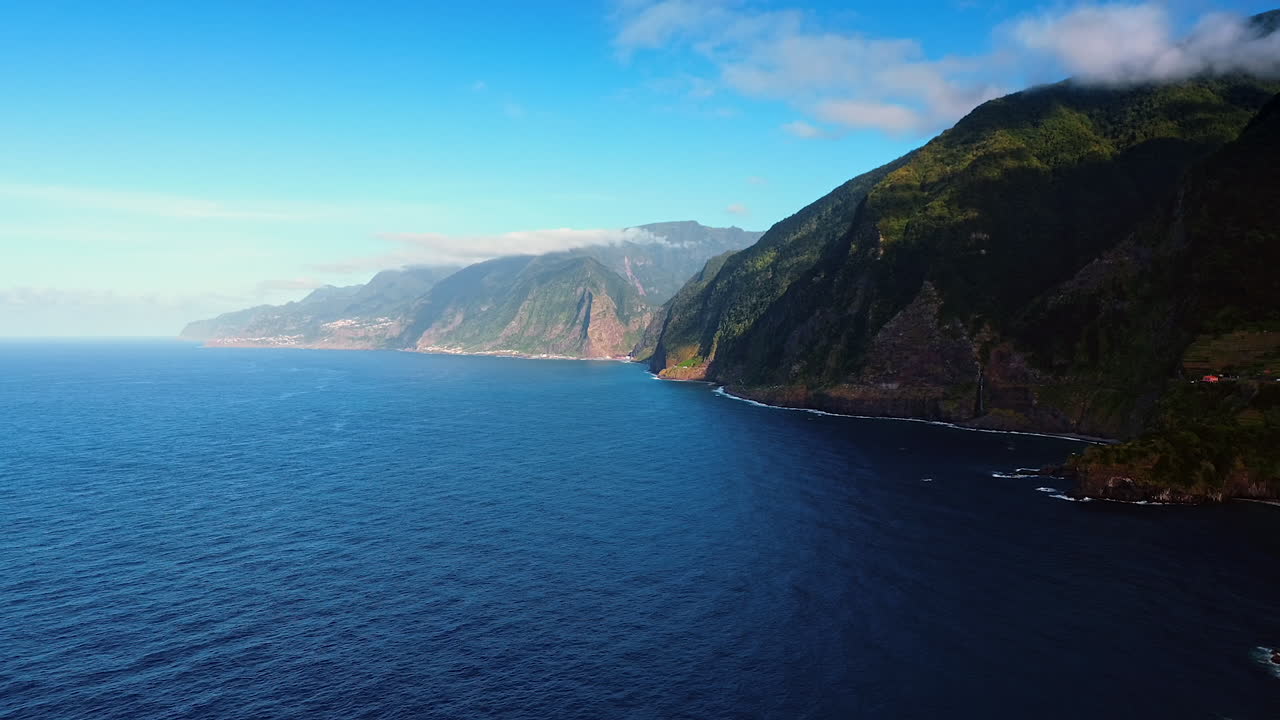 Footage above the blue waterscape of the North Atlantic Ocean at the rocks of Madeira Islands, Portugal. Low angle view at the beautiful mountains with steep cliffs.
