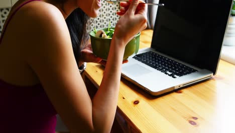 woman using laptop while having breakfast