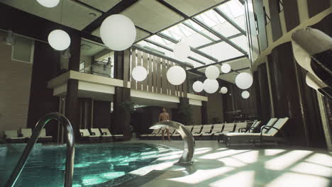 attractive man walking by indoor pool. man resting near swimming pool.