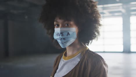 portrait d'une femme afro-américaine portant un masque de protestation dans un garage vide