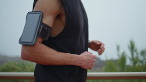 man body running outdoors with sport accessory closeup. sporty guy jogging park