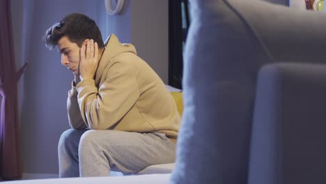 집에서 소파에 앉아 있는 우울하고 외로운 남자.