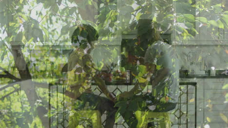 sitting at table, two people with leafy plants and animation in scene