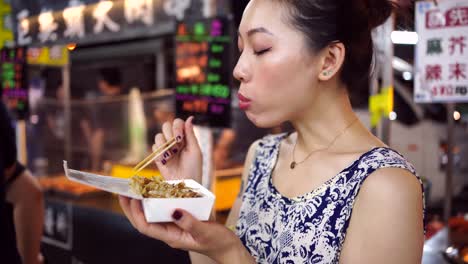 asian woman eating takoyaki in night market