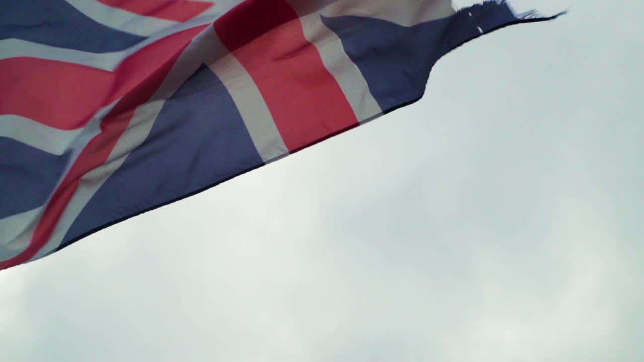 Primo piano di vecchia bandiera Union Jack logora che sventola con vento forte al rallentatore