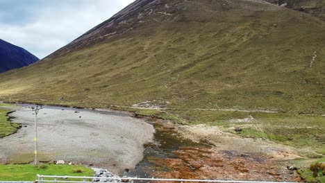 Tilt-up-drone-shot-flying-under-bridge-in-mountain-valley