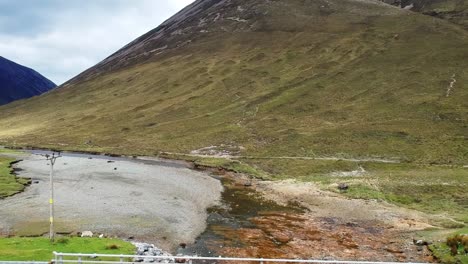 tiro de dron inclinado volando bajo el puente en el valle de la montaña