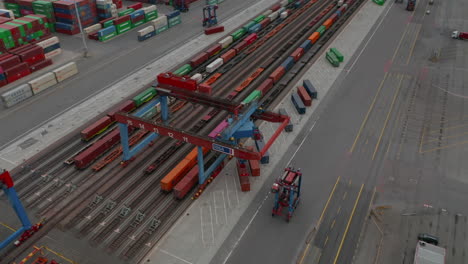 Aerial-view-of-forklift-driving-in-commercial-cargo-terminal-by-colorful-cargo-containers