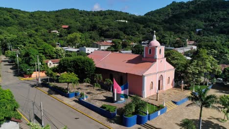 órbita aérea alrededor de la iglesia católica púrpura en la ciudad tropical de san juan del sur