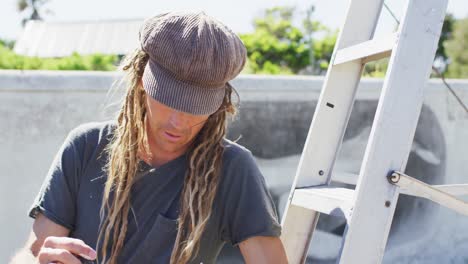 retrato de video de un artista masculino caucásico sonriente con rastas frente al mural en la pared