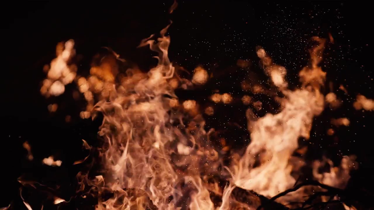 Primo piano di un falò con fiamme danzanti e scintille volanti di notte