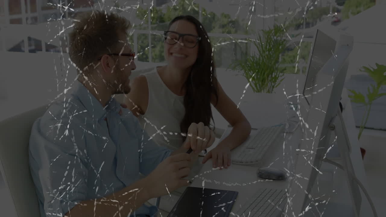 Working together at desk, man and woman using computers and digital tablet with animation software