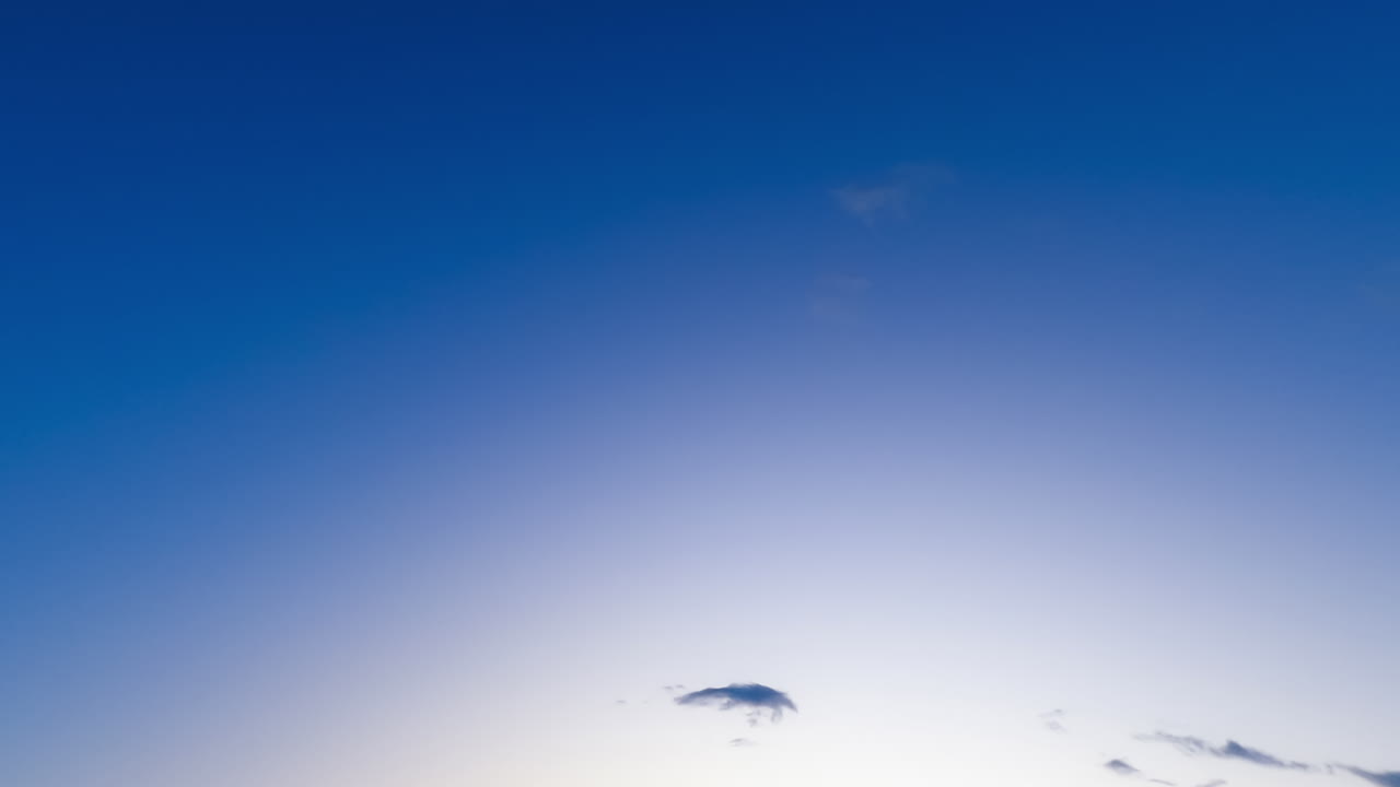 Wonderful blue sky with small clouds appearing and disappearing quickly. Low angle view on the horizon at day. Timelapse.