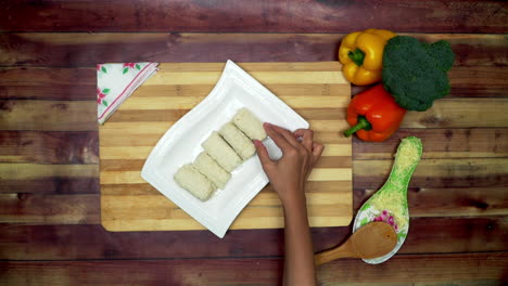 A-Top-view-of-placing-the-non-fried-spring-roll-in-to-the-tray,-two-big-yellow-and-red-capsicums-and-a-green-broccoli-on-the-table