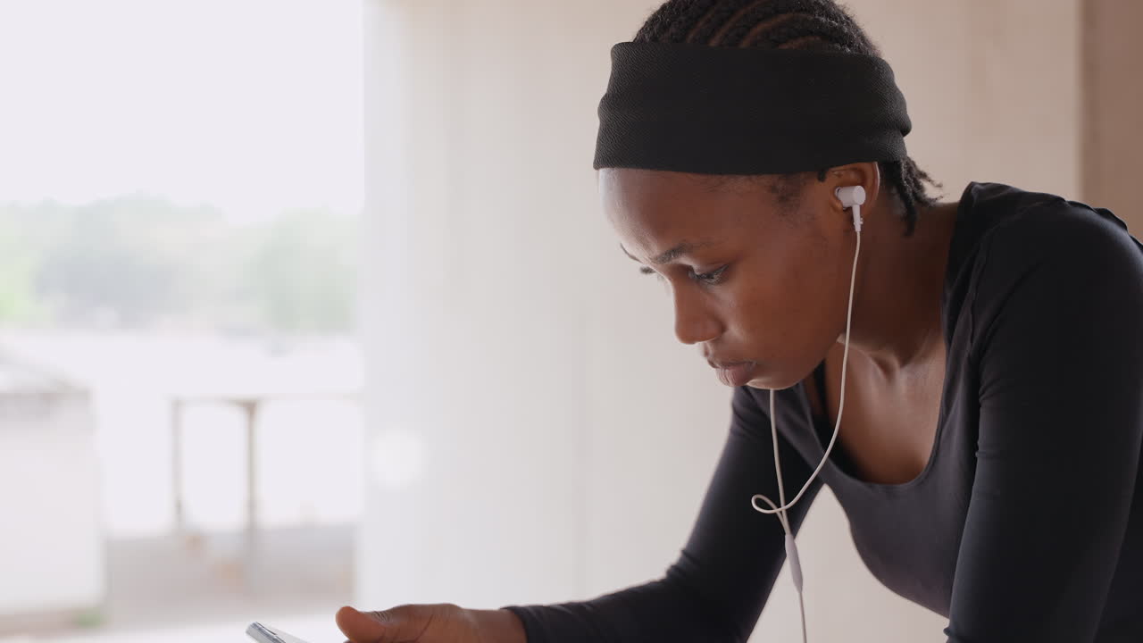 Donna concentrata nello studio. Donna che vive in città intensamente impegnata con appunti sul telefono e auricolari. Donna urbana che si concentra sul telefono e sugli appunti ascoltando con gli auricolari durante una sessione di studio.