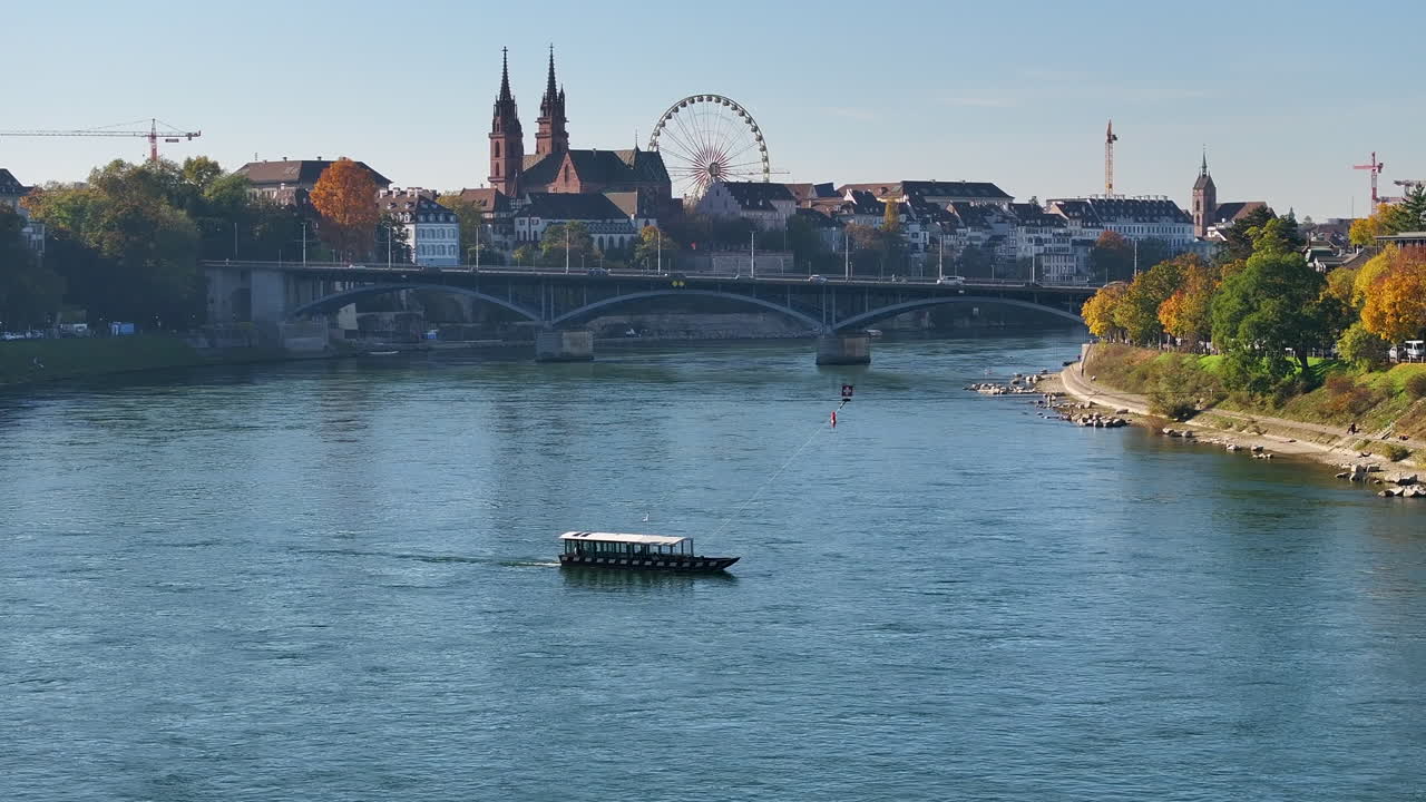 A slow pan of a ferry crossing the Rhine River in Basel on a bright autumn day with fall colors