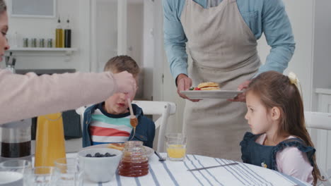 Familia-Desayunando-Juntos-Comiendo-Panqueques-Madre-Y-Padre-Preparando-Comida-Casera-Para-Niños-El-Fin-De-Semana-Por-La-Mañana-4k