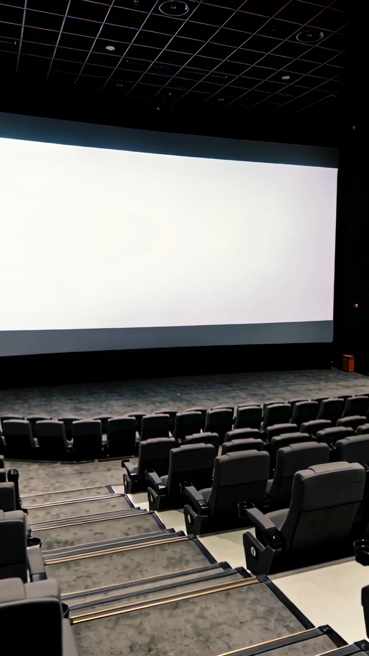 Video verticale: Telecamera panoramica che si avvicina a uno schermo di proiezione vuoto al cinema, rivelando i sedili.