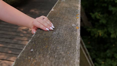 a young girl has put her hand on the railing of the bridge on the hand has an engagement ring