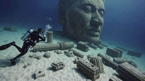 scuba diver exploring underwater ancient statues and ruins