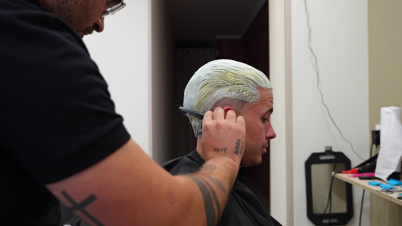 Hairdresser using a comb to remove the first bleach layer while protecting fragile hair from breakage
