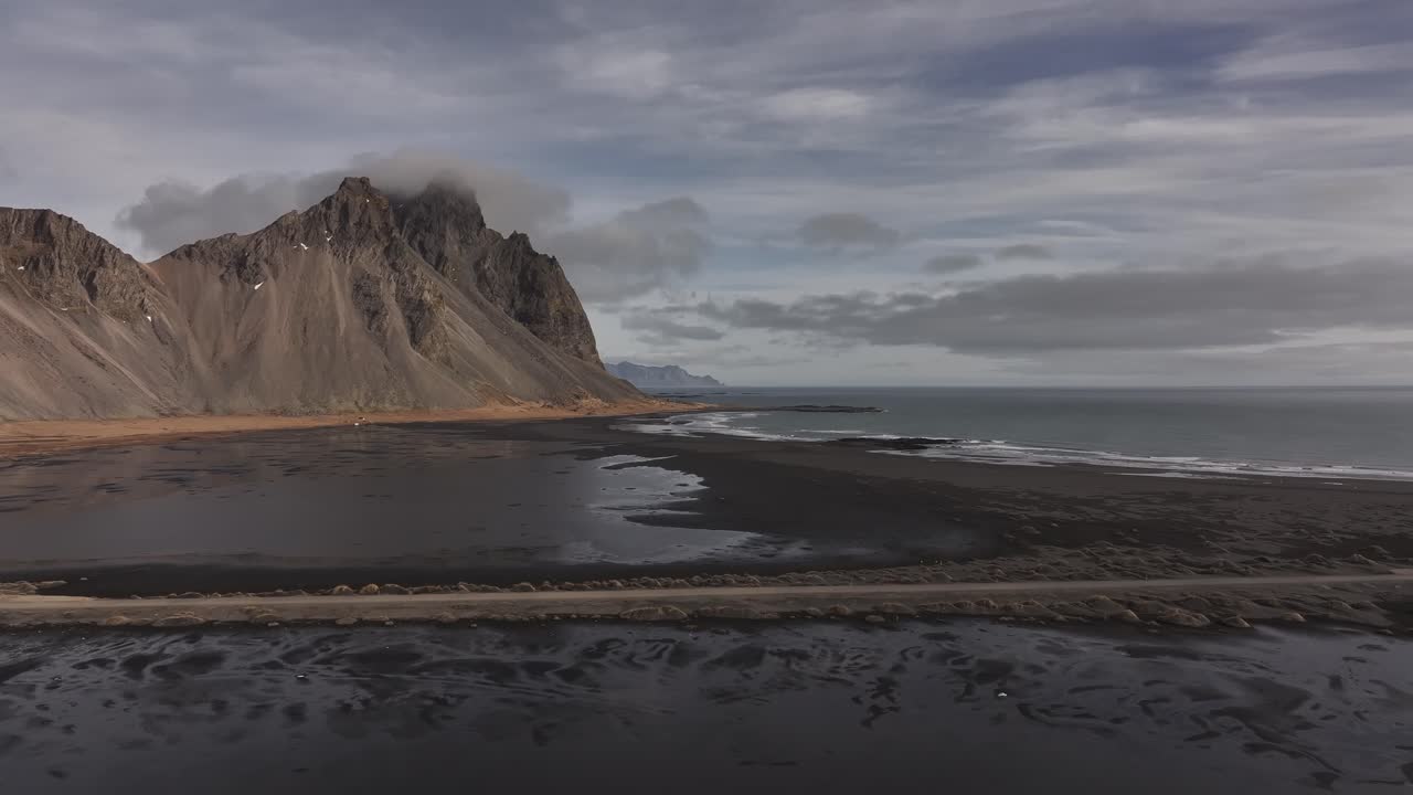 black sand meets sea beneath misty peaks on stokksnes coast in iceland
