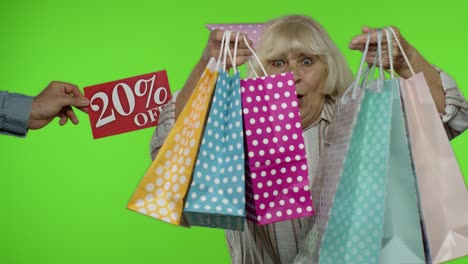 inscripción 20 por ciento de descuento aparece al lado de la abuela. mujer celebrando con bolsas de compras