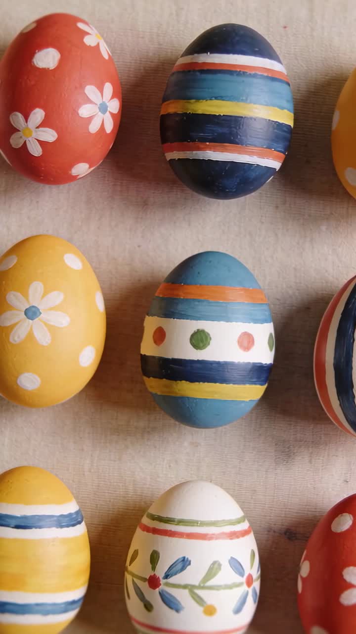 Vertical video: Tilting camera causing zoom on beige table focusing nine painted eggs' patterns