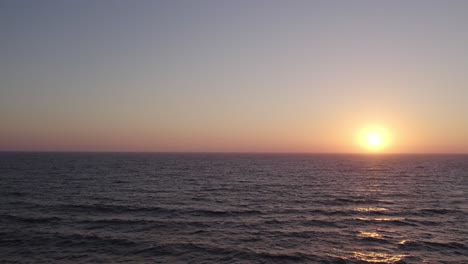 Teal-Ocean-Waves-under-a-Pink-Sunset-in-Oxnard,-California-~-4K-Drone-Footage-Quick-Pan-Upwards-to-Reveal-Sunset