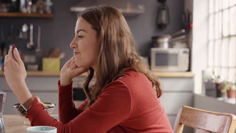 mujer feliz usando una aplicación de teléfono inteligente para llamar a un ser querido y hablar con alimentación de video en casa en la cocina
