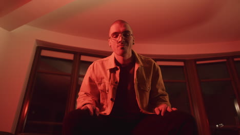 man in a yellow jacket, sitting in a room with red lights