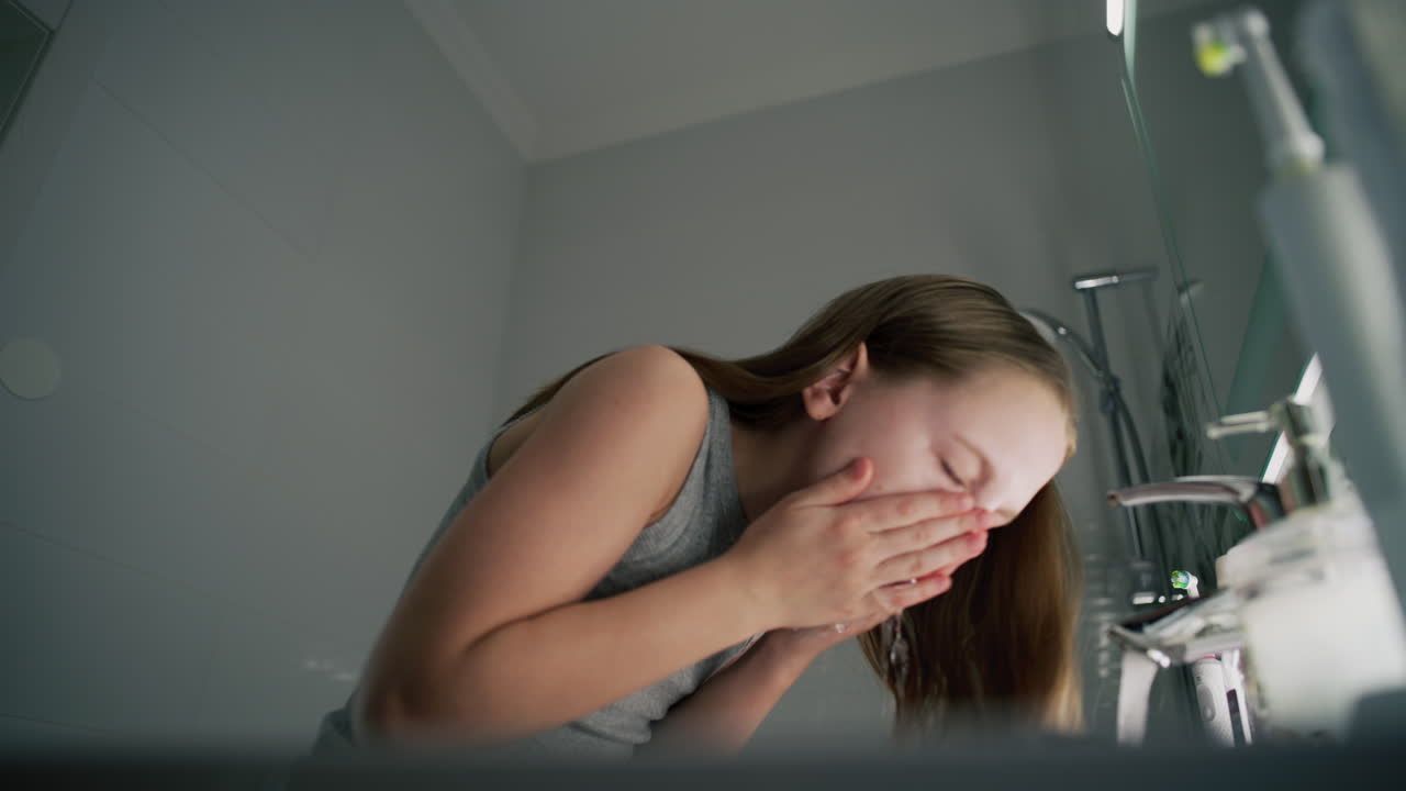 십대 소녀가 목욕실에서 머리를 고 얼굴을 고 있다